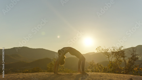 Young good looking woman perform yoga pose on mountain with sun light during sunset © stnazkul