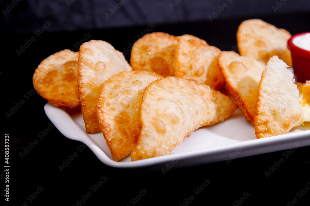 Deliciosos pasteis de carne, camarão, queijo com creme de queijo gorgonzola em recipiente branco em fundo escuro. Deliciosos pasteis de carne, camarão, queijo com creme de queijo gorgonzola em recipiente branco em fundo escuro.