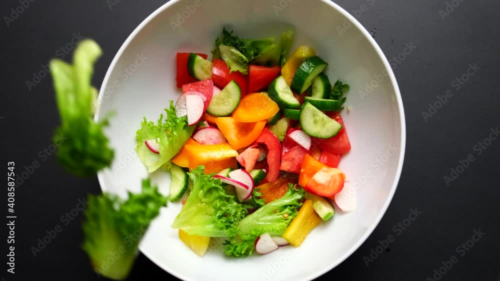 chopped vegetables fall into a white salad bowl. white plate on black background. High quality 4k footage chopped vegetables fall into a white salad bowl. white plate on black background. High quality 4k footage