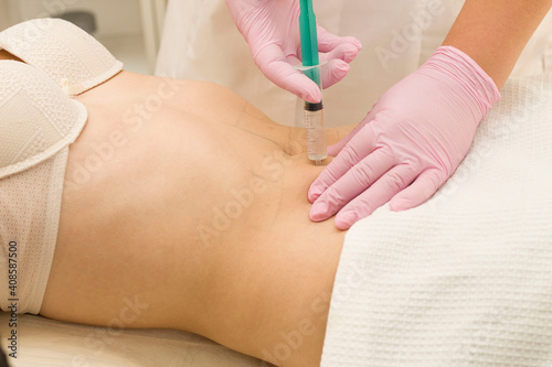A shot in the stomach. A woman at a cosmetologist receives lipolytics in the stomach. Fat-burning