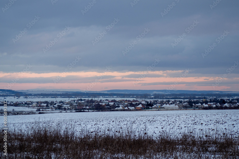 Winter village and fields landscape during sunset