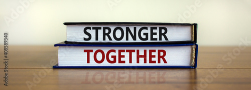 Stronger together symbol. Concept words 'stronger together' on books on a beautiful wooden table, white background. Business, motivational and stronger together concept. © Dzmitry