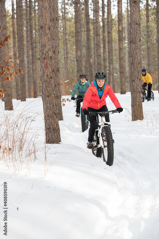 Group of attractive women riding fat bikes in the snow