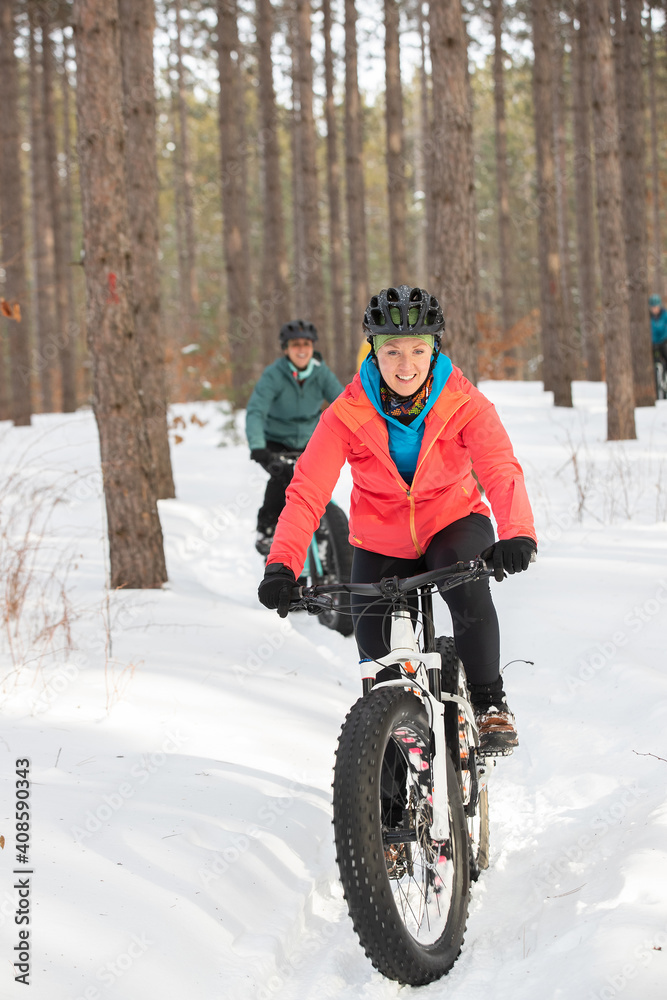Group of attractive women riding fat bikes in the snow
