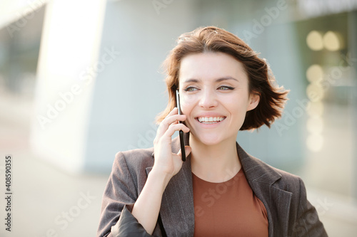 Young smiling businesswoman in smart casualwear consulting client on the phone