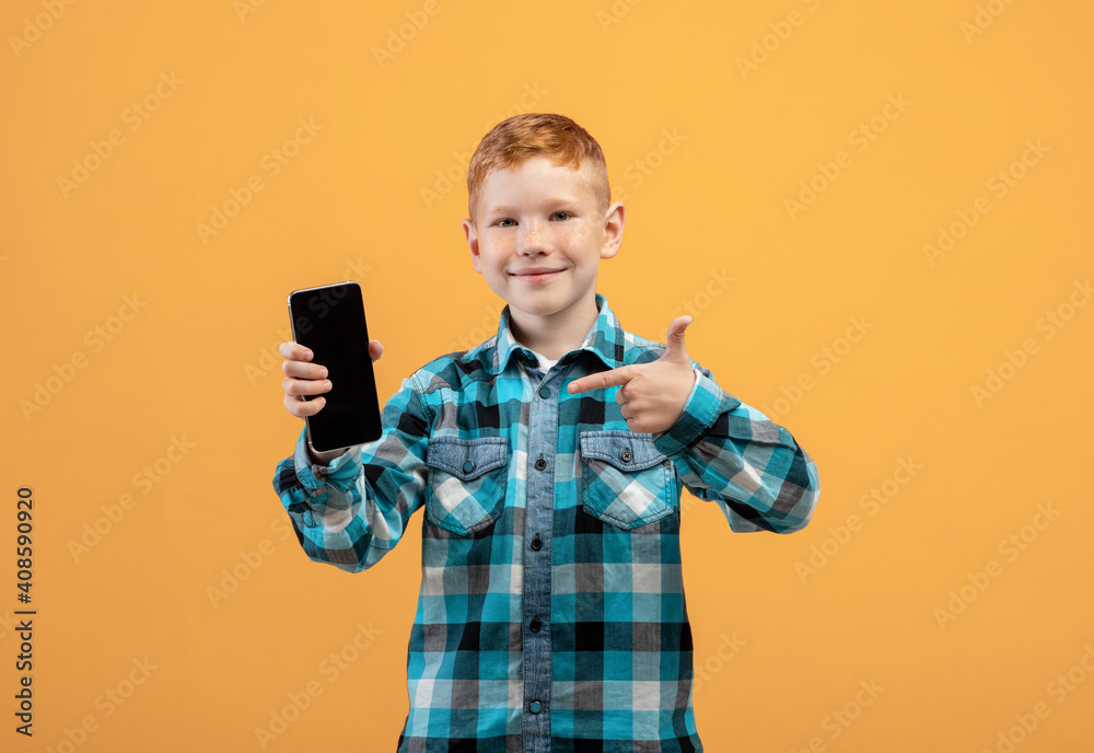 Smiling boy pointing at mobile phone with empty screen Smiling boy pointing at mobile phone with empty screen