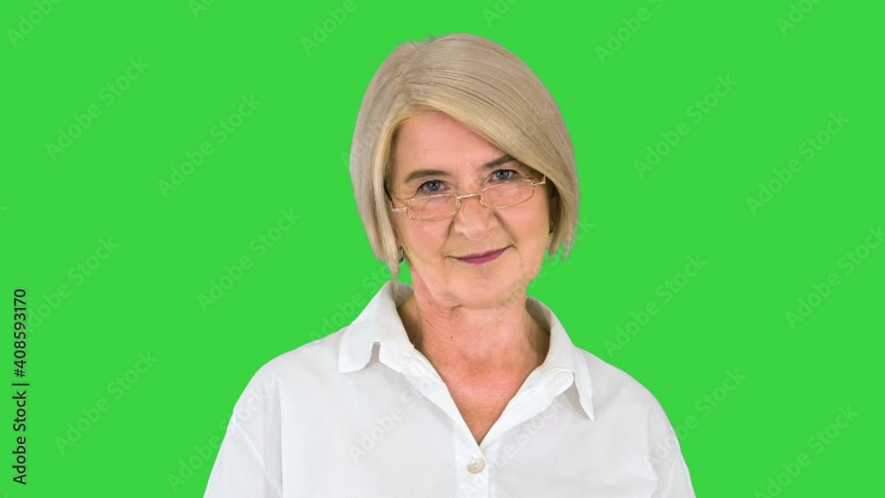 Happy Mature Woman in White Shirt Smiling on a Green Screen, Chroma Key. Happy Mature Woman in White Shirt Smiling on a Green Screen, Chroma Key.