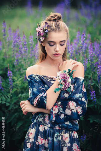 Beautiful woman with purple flowers in a lupine spring field. Beauty outdoor portrait