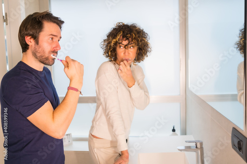 Lifestyle, a young Caucasian couple in pajamas cleaning their teeth very happily