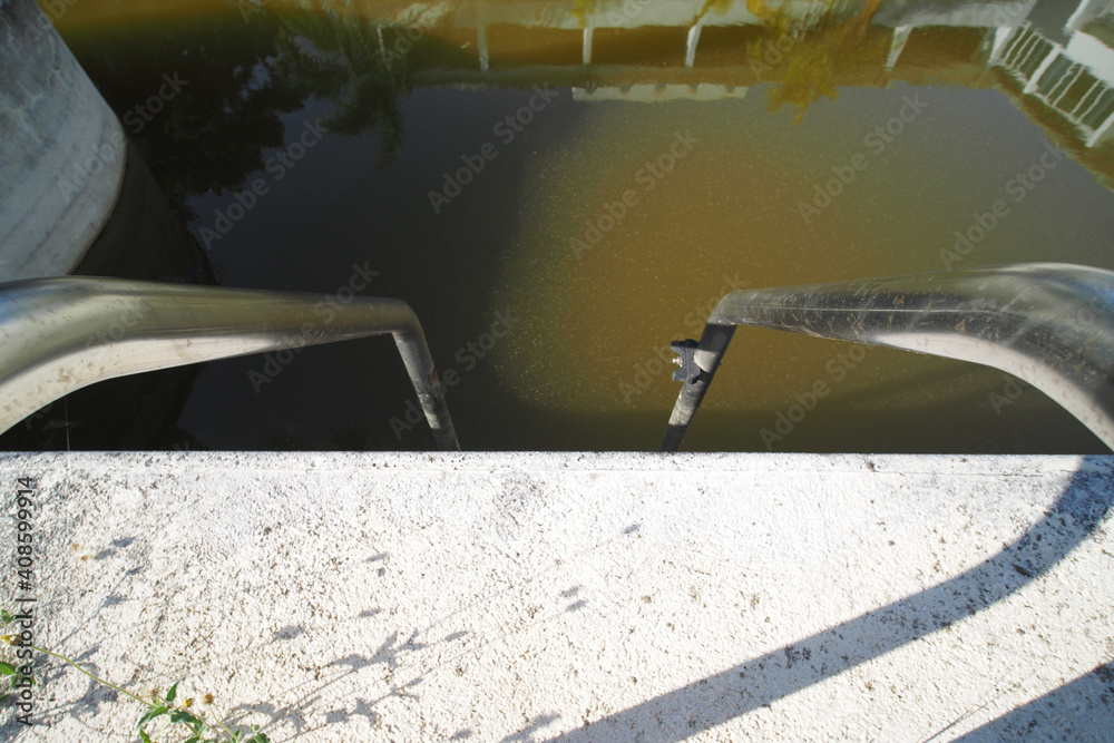 Metal steel handrail in dirty swimming pool with green water. Metal steel handrail in dirty swimming pool with green water.