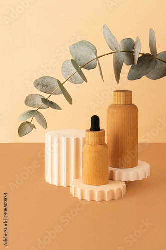 Wooden cosmetics containers on the pastel isometric background.Geometrical podium and fresh eucalyptus branch behind.Earth colors,zero waste containers.Mockup concept.