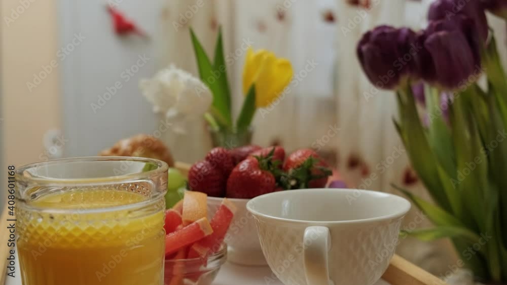 Close up of a wood tray with hot coffee, orange juice, fruits croissant and flowers prepared for a breakfast in bed. Close up of a wood tray with hot coffee, orange juice, fruits croissant and flowers prepared for a breakfast in bed.