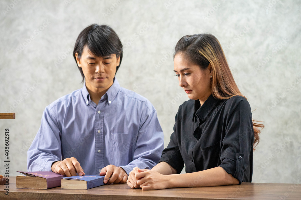 Asian beautiful Christian woman praying with Reverend in the church with wood cross and BIBLE Asian beautiful Christian woman praying with Reverend in the church with wood cross and BIBLE