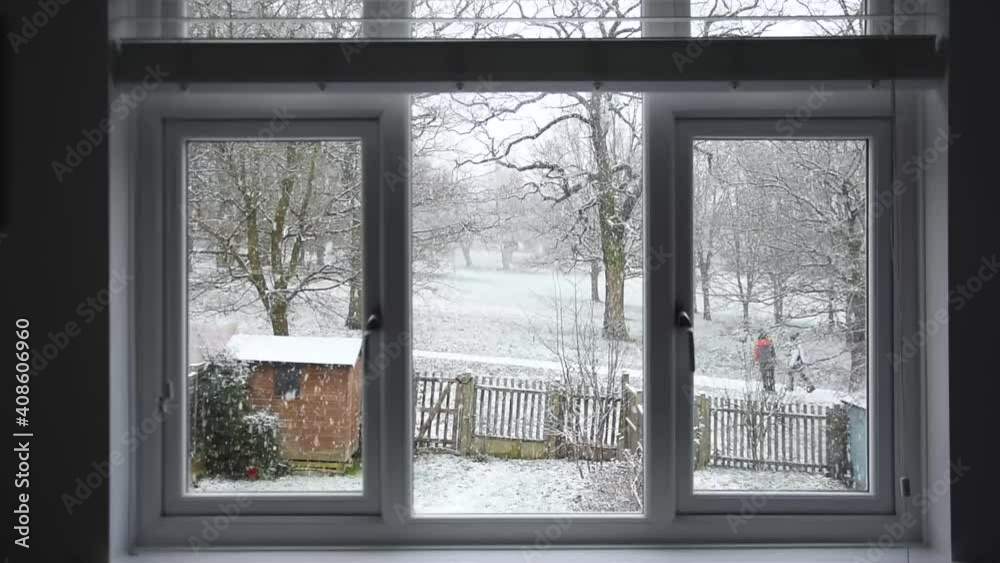 Winter view from a window - people in ski jackets walking in the snow in the park