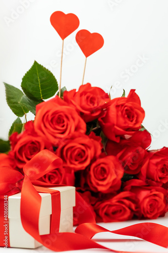 bright scarlet bouquet of roses  gift box with a bright ribbon on a white background with a place for text  greeting card concept happy Valentine s day  March 8  happy birthday. selective focus