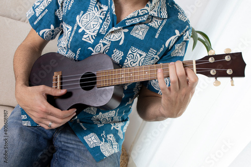 Boy in Hawaiian shirt playing ukulele
