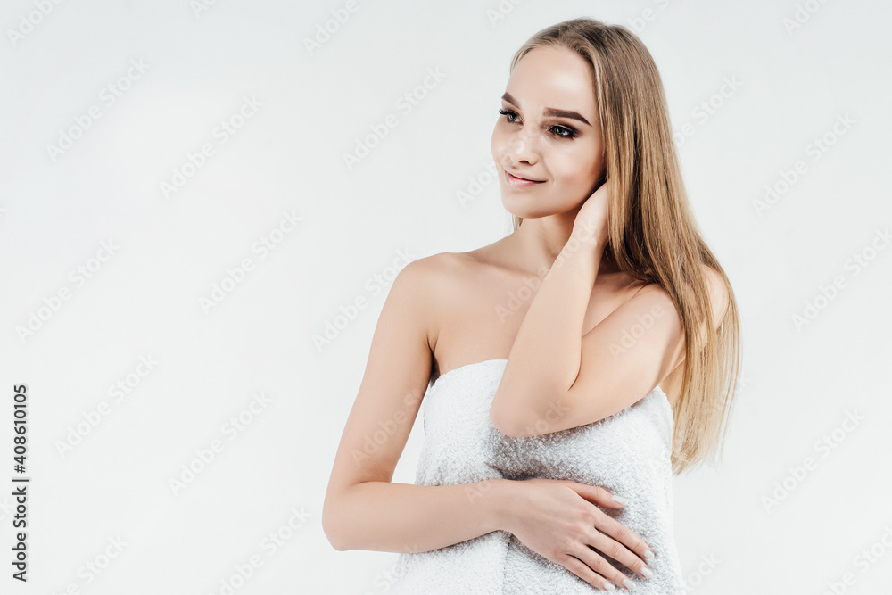Portrait of a satisfied woman wrapped in a towel on a white background, spa treatment. Healthy and radiant skin. Place for text Portrait of a satisfied woman wrapped in a towel on a white background, spa treatment. Healthy and radiant skin. Place for text
