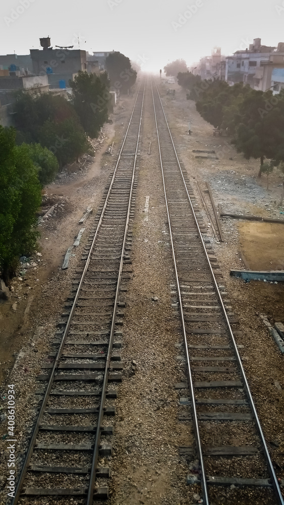 Parallel railway tracks leading into the foggy morning