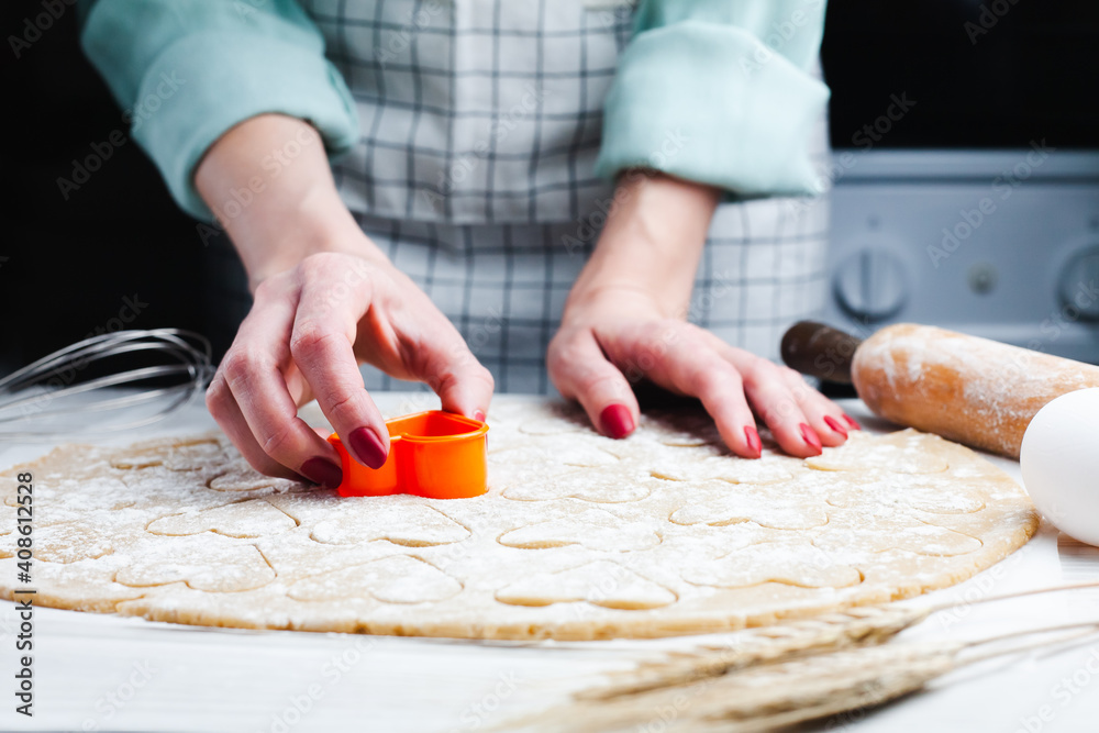 Woman's hands cutting hearts from the dough. Homemade pastry. Cooking process. Close-up.