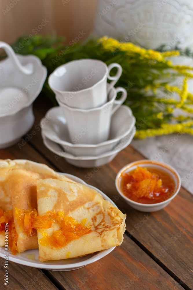 Thin pancakes with orange jam or marmalade on wooden background. Tasty breakfast. Maslenitsa. Thin pancakes with orange jam or marmalade on wooden background. Tasty breakfast. Maslenitsa.