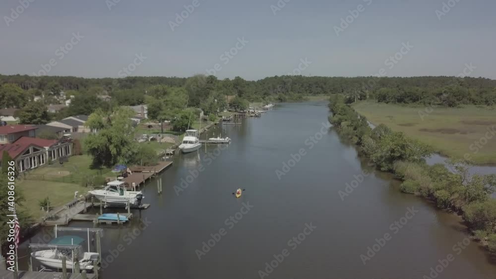 Drone shot of person kayaking on a stretch of water by the sea Drone shot of person kayaking on a stretch of water by the sea