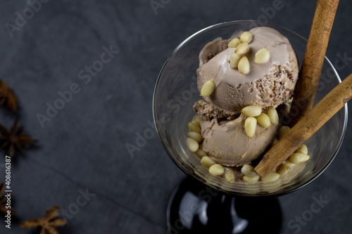 ice cream in tall ice cream bowl with pine nuts and spices on a black background