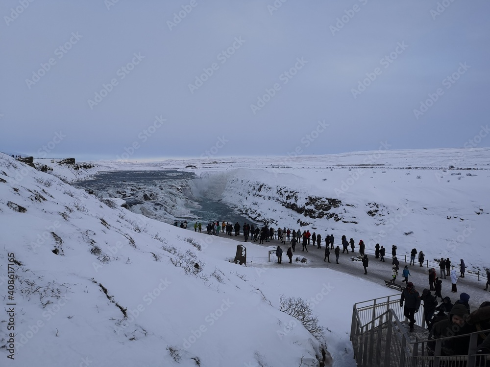 frozen waterfall with people in Iceland in winter