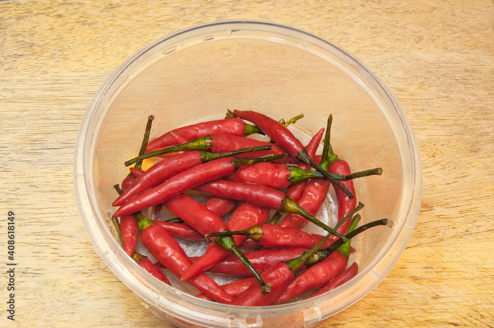 Red chili pepper in plastic container on a wooden background.
Top side view. Red chili pepper in plastic container on a wooden background.
Top side view.