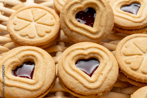 Close-up detail of heart-shaped cookies and strawberry jam, on a basket, for Valentine's Day, horizontal