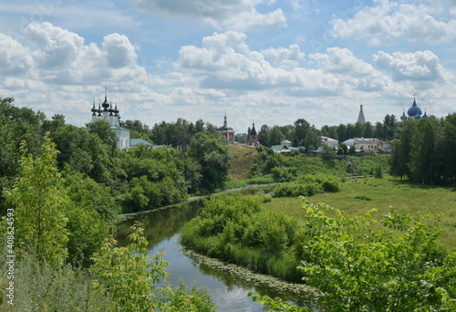 Orthodox Russian churches standing along the river, pleasant summer village landscape. The 