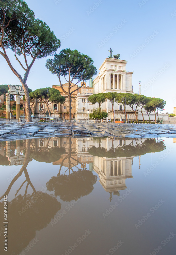 Obraz premium Rome, Italy - in Winter time, frequent rain showers create pools in which the wonderful Old Town of Rome reflect like in a mirror. Here in particular Via dei Fori Imperiali