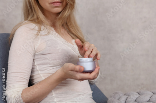 Winter hand skin care routine. Woman applying moiturizing cream close up