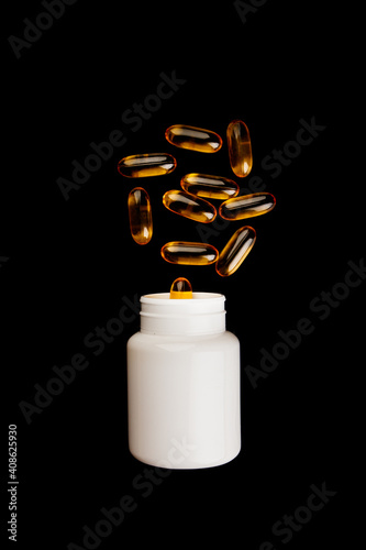 Healthy diet concept. Fish oil capsules with omega 3 and vitamin D in a plastic bottle on a black background.
