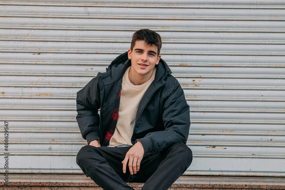 young man sitting on the city street young man sitting on the city street