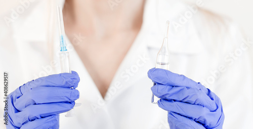 Hand holding syringe and vaccine.
