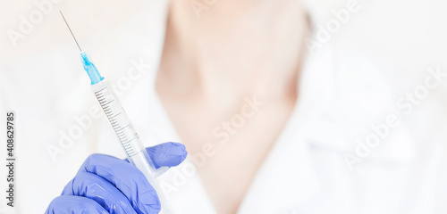 Hand holding syringe and vaccine.