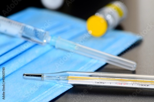 Coronavirus vaccine with syringe drugs for the design of information materials on the benefits of vaccination against viral diseases, thermometer and medical mask are the main working tools a doctor