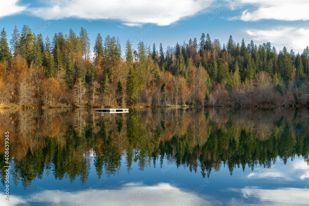 Fototapeta premium Fall color forest and foliage landscape surround an idyllic mountain lake Crestasee in the Alps of Switzerland on a late autumn day with reflections in the water. Flims, Switzerland