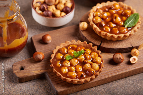 Mini tarts with nuts and caramel cream filling. Sweet homemade dessert.