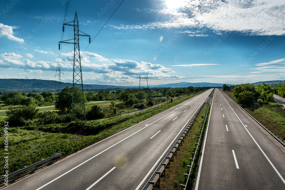 Empty silent Asphalt highway road with beautiful sky and a row of electricity pylons Empty silent Asphalt highway road with beautiful sky and a row of electricity pylons