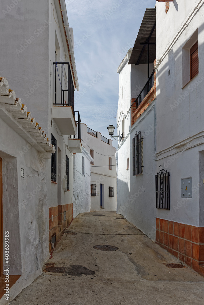 A narrow street of terraced traditional Spanish Houses, shaded from the midday sun in the Montain Village of Sayalonga in Andalucia.