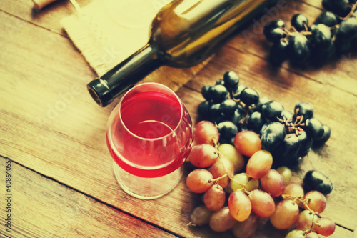 Glass of wine, bottle, grapes on a background of boards.