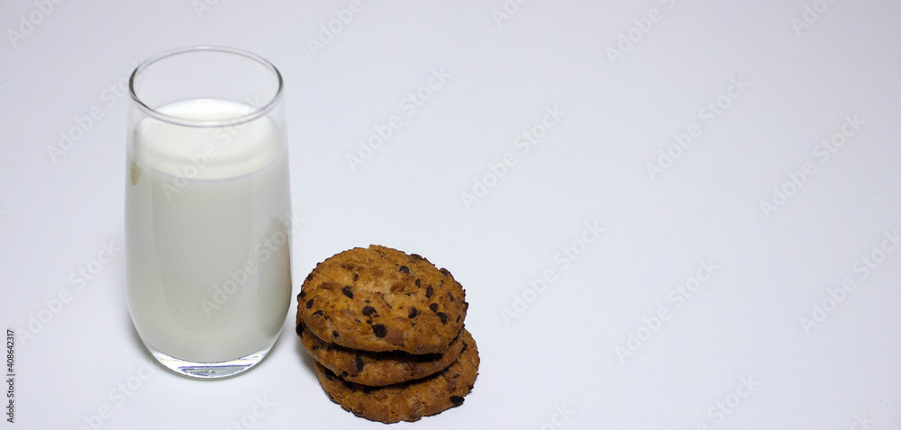 A glass of milk and three oat biscuits on a white background A glass of milk and three oat biscuits on a white background
