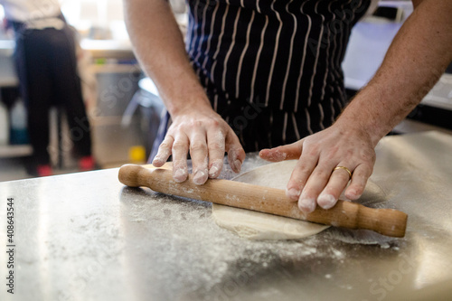 Fresh dough being rolled out on a stainless steel worktop