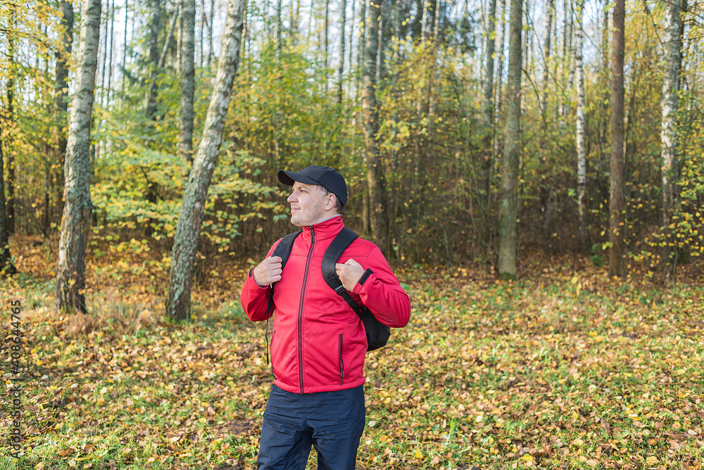 Young man with a backpack walks through the forest. Travel theme. Young man with a backpack walks through the forest Young man with a backpack walks through the forest. Travel theme. Young man with a backpack walks through the forest