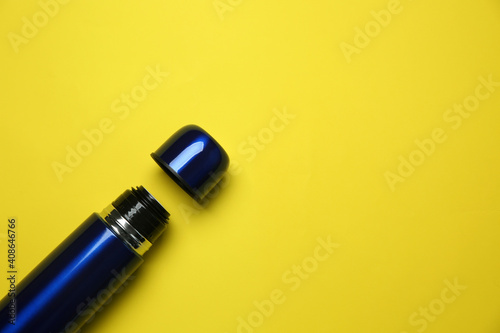 New modern thermos and cup on yellow background, flat lay. Space for text