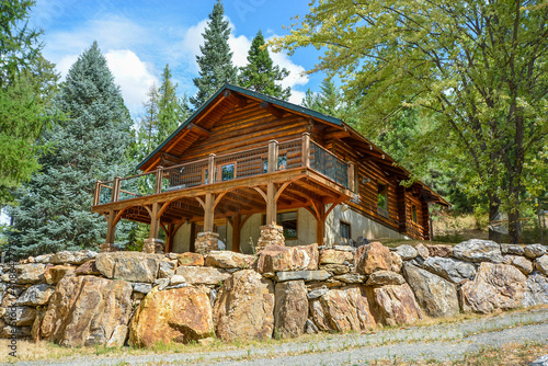 A picturesque vacant and rustic log home in the mountains surrounded by pine trees on a rocky hillside in Coeur d'Alene, Idaho.