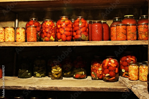Home made vegetables canned in glass jars are displayed on shelves in the basement