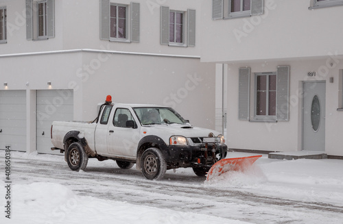 Принти на полотні A pickup truck equipped with a plow is removing snow from a sloped driveway in winter