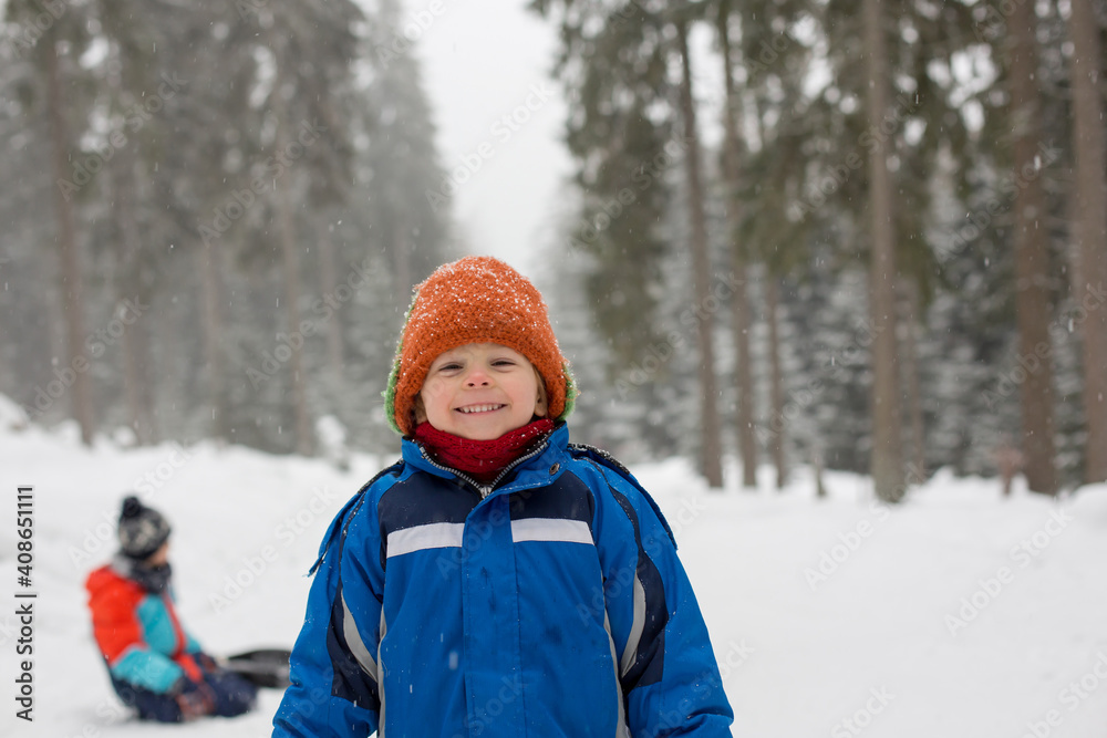 Beautiful toddler child, blond boy with cute hat, playing in the snow